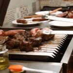 a person grilling meat on a grill with tongs