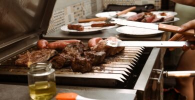 a person grilling meat on a grill with tongs